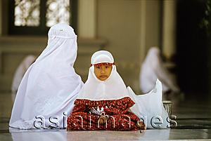 Asia Images Group - Indonesia, Aceh,Banda Aceh,Muslim girl dressed in mukenahs or kerudungs (prayer robes) sits with mother at Baiturrahman Great Mosque.