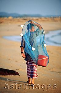 Asia Images Group - Malaysia, Marang River, fisherman walks along the beach carrying net and bucket.
