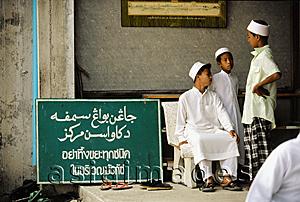 Asia Images Group - Thailand, Yala, Muslim children sit next to a sign cautioning worshippers to dispose of their trash before entering the mosque.