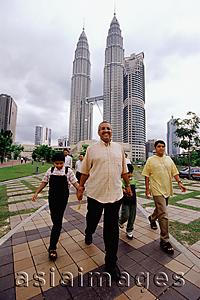 Asia Images Group - Malaysia, Kuala Lumpur, Malay family walking, Petronas Twin Towers in background.