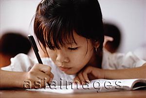 Asia Images Group - Vietnam, Ho Chi Minh City, A young girl concentrating on her studies.