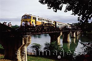 Asia Images Group - Thailand, Kanchanaburi, River Kwai, Tourists watching as a train on the Burma-Siam railroad crosses the bridge.