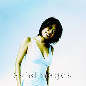 Asia Images Group - Young woman in white dress against light blue background