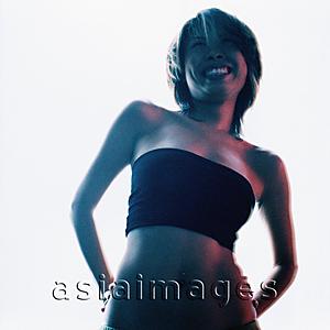 Asia Images Group - Woman in black tube top with hands behind her back against white background