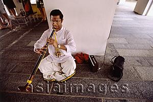 Asia Images Group - Singapore, Little India, Man sitting on floor playing clarinet.