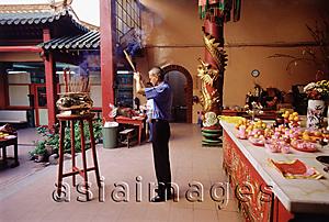 Asia Images Group - Malaysia, Kuala Lumpur, Chinatown, Man praying with joss sticks at Chinese temple.