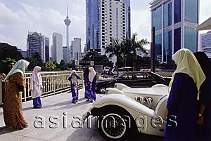 Asia Images Group - Malaysia, Kuala Lumpur, Muslim girls taking a picture with vintage car in downtown Kuala Lumpur.