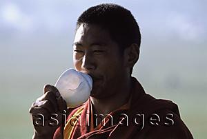Asia Images Group - China, Szechuan (Sichuan), Kham region, Tibetan monk blowing on conch shell as a prayer call during the summer nomad festival.