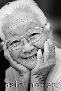 Asia Images Group - Mature woman with glasses, with hands on head, smiling.