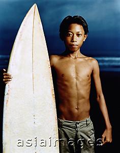 Asia Images Group - Indonesia, Bali, Kuta Beach, Young surfer holding surfboard on the beach.