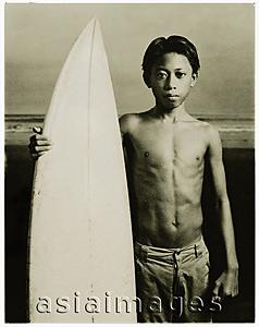 Asia Images Group - Indonesia, Bali, Kuta Beach, Young surfer holding surfboard on the beach.