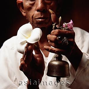 Asia Images Group - Indonesia, Bali, Ubud, Hindu priest holding prayer bell and Frangipani flower.