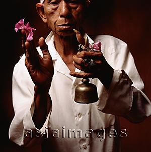 Asia Images Group - Indonesia, Bali, Ubud, Hindu priest holding prayer bell and  flower.