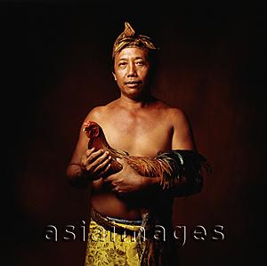 Asia Images Group - Indonesia, Bali, Ubud, Balinese man holding fighting cock.