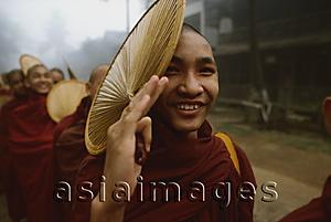 Asia Images Group - Myanmar (Burma), Bago, Buddhist monk holding a fan, in line to collect alms.
