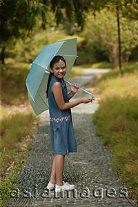 Asia Images Group - Young girl holding an umbrella, looking over shoulder