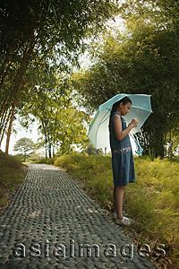 Asia Images Group - Young girl holding an umbrella, looking at something