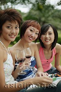Asia Images Group - Young women sitting, looking at camera, wine glasses in hand
