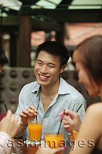Asia Images Group - Young man sitting with friends, having a drink