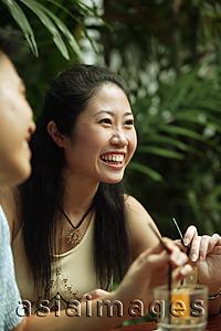 Asia Images Group - Young woman at cafe, smiling.