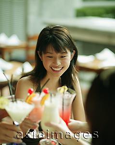 Asia Images Group - Young woman and friends toasting with drinks.