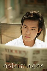 Asia Images Group - Young man reading newspaper