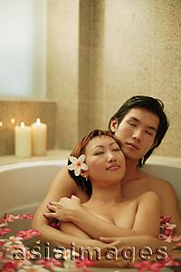 Asia Images Group - Couple hugging in tub, flowers floating around