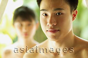 Asia Images Group - Young man looking at camera, woman in the foreground