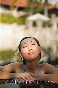 Asia Images Group - Young woman, at edge of swimming pool, eyes closed