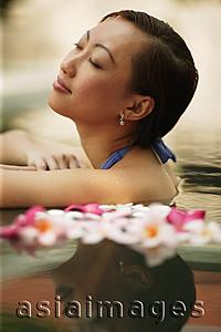 Asia Images Group - Young woman, at edge of swimming pool, eyes closed