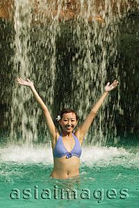 Asia Images Group - Young woman in swimming pool, water cascading on her