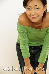 Asia Images Group - Young woman looking at camera, bending forward