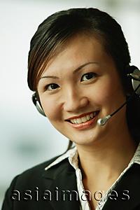 Asia Images Group - Young woman wearing hands-free device, looking at camera