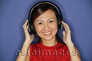 Asia Images Group - Young woman wearing headphones,  smiling