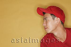 Asia Images Group - Young man wearing a red cap, against a yellow background