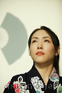 Asia Images Group - Young woman wearing a kimono, looking up.