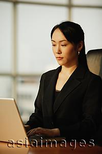 Asia Images Group - Young woman sitting at desk, using laptop
