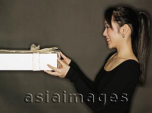 Asia Images Group - Young woman holding a gift, black background