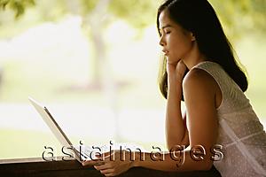 Asia Images Group - Young woman, hand on chin, looking at laptop