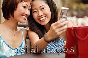 Asia Images Group - Young women smiling looking at mobile phone