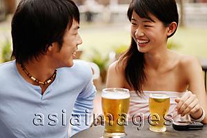 Asia Images Group - Couple sitting at cafe, looking at each other, drinks in hand