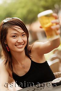 Asia Images Group - Young woman raising a glass of beer, looking at camera