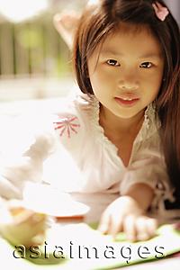 Asia Images Group - Young girl looking at camera, holding a pen