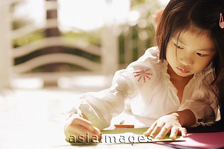 Asia Images Group - Young girl looking down, writing
