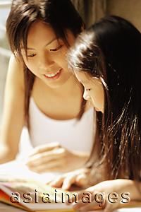 Asia Images Group - Mother and daughter, side by side, looking at magazine