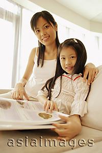 Asia Images Group - Mother and daughter, sitting side by side, looking at camera, smiling