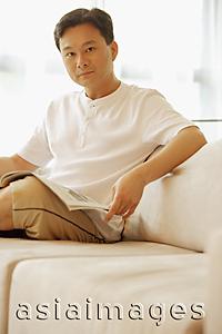 Asia Images Group - Man sitting on sofa, looking at camera