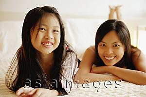 Asia Images Group - Mother and daughter lying on bed, looking at camera