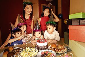 Asia Images Group - Young girl blowing out candles at a birthday party.