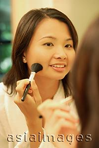 Asia Images Group - Woman putting on make-up with a blush brush